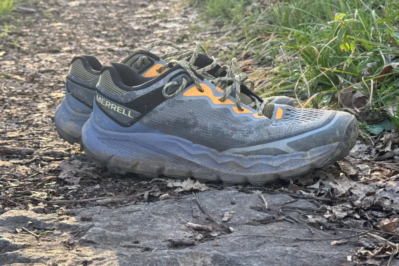 A pair of Merrell Nova 4 trail running shoes rests on a rocky path, ready for adventure.