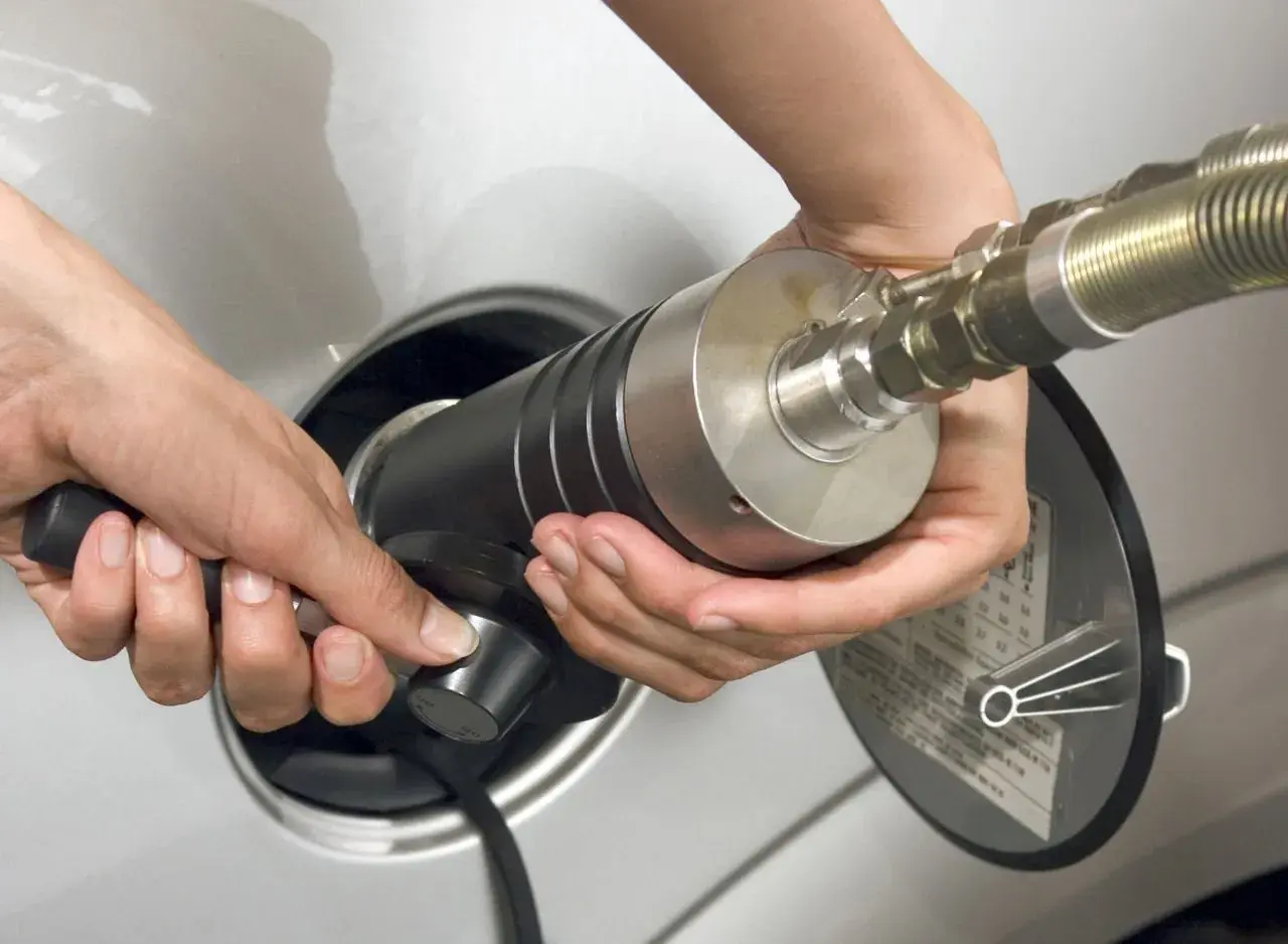Mani che inseriscono un ugello per il rifornimento di gpl metano in un'auto.