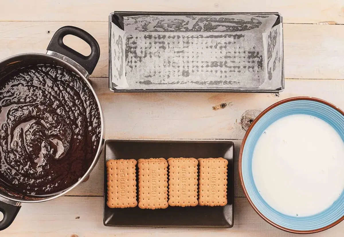 Preparando una deliciosa tarta de galletas y chocolate: chocolate derretido, galletas, molde y leche.
