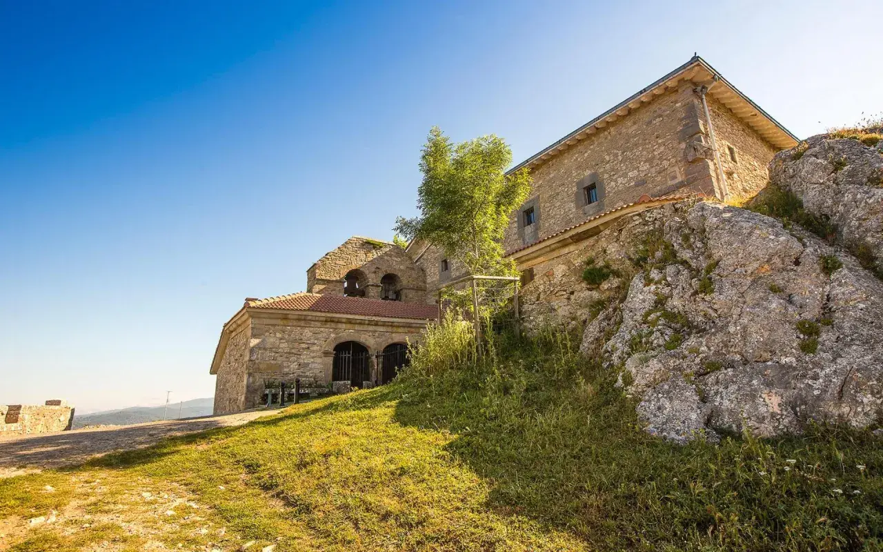 Antiguo santuario de oro en la cima de una colina rocosa, con un cielo azul brillante.