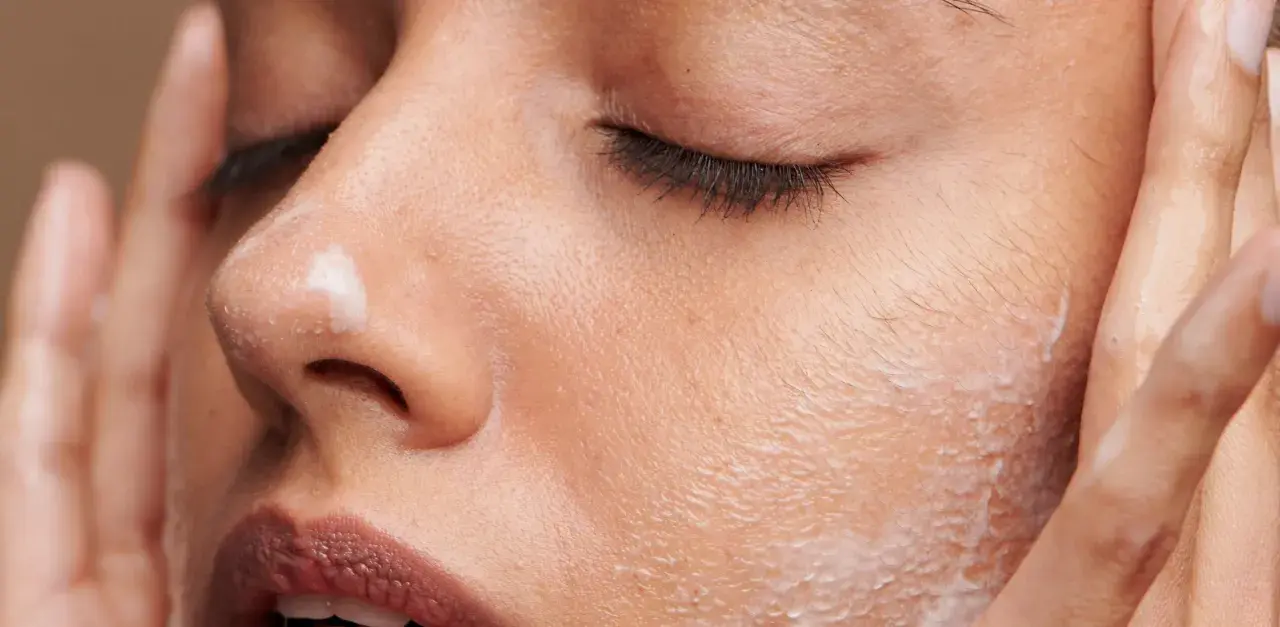 Une femme applique une crème sur son visage. C'est le moment idéal pour savoir quand appliquer crème solaire visage pour une protection optimale.