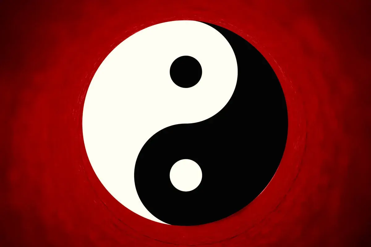 Il simbolo Yin e Yang, principio della filosofia orientale, su sfondo rosso sfumato.