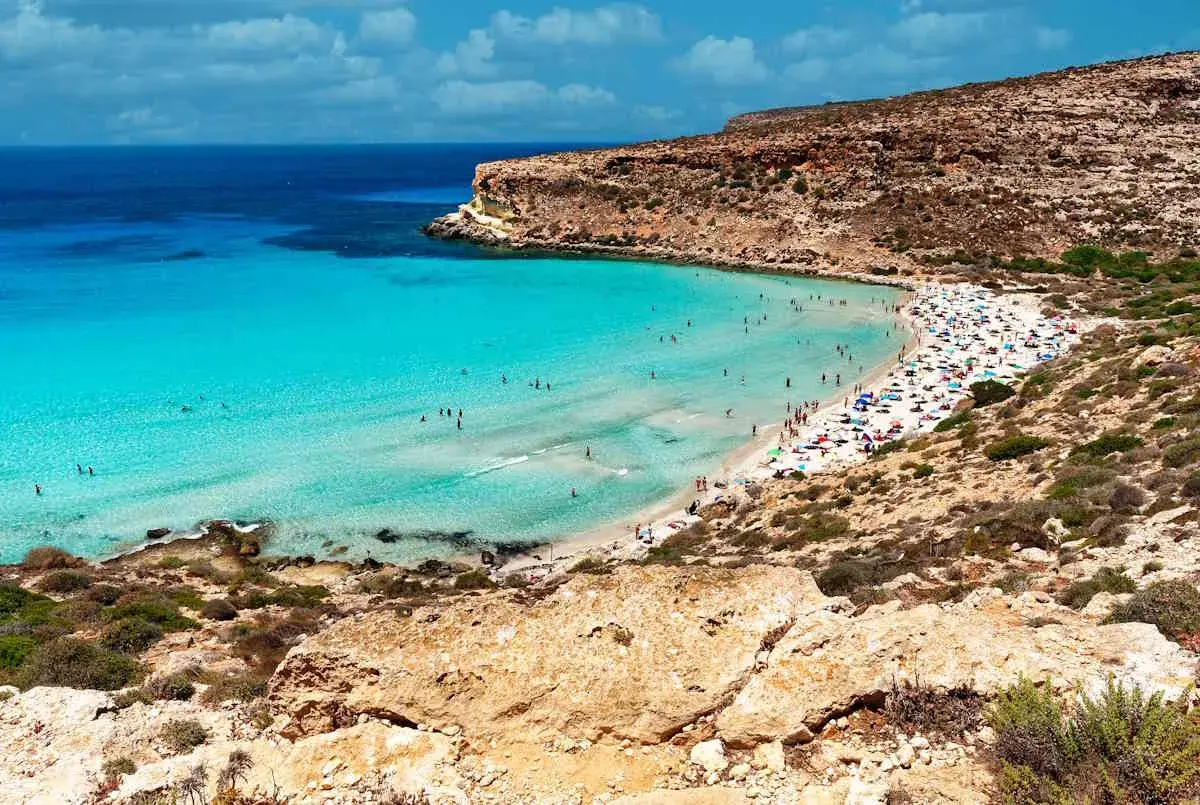 Spiaggia con acque cristalline e scogliere, un vero gioiello per la classifica delle spiagge più belle del mondo.
