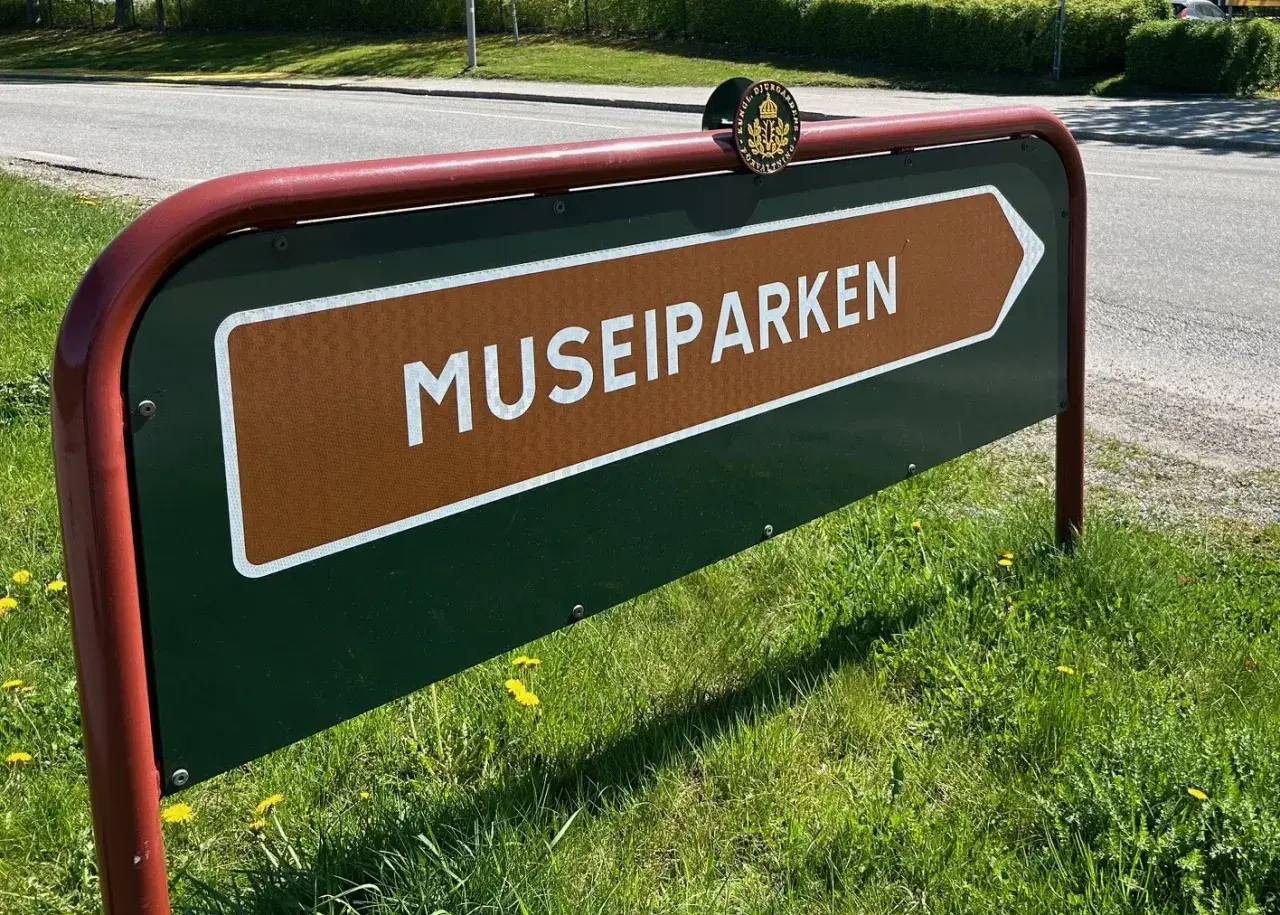 Skylt som pekar mot Museiparken Stockholm. En grön skylt med en brun pil och texten "MUSEIPARKEN" i vitt.