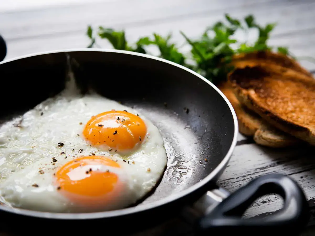 Deux œufs au plat parfaits dans une poêle, prêts à être dégustés. Une idée simple pour comment faire des oeufs au plat.