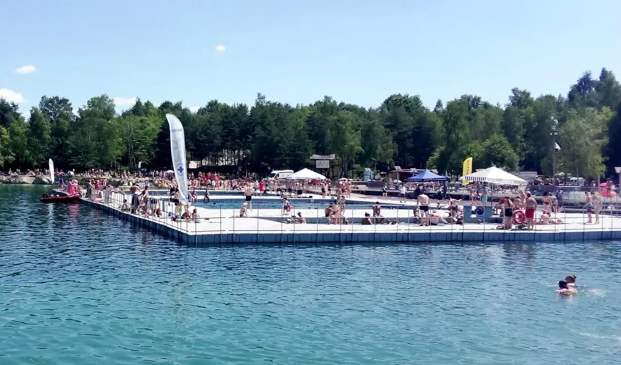 Słoneczny dzień na Balatonie w Trzebini. Ludzie odpoczywają na pływającym pomoście i w wodzie.
