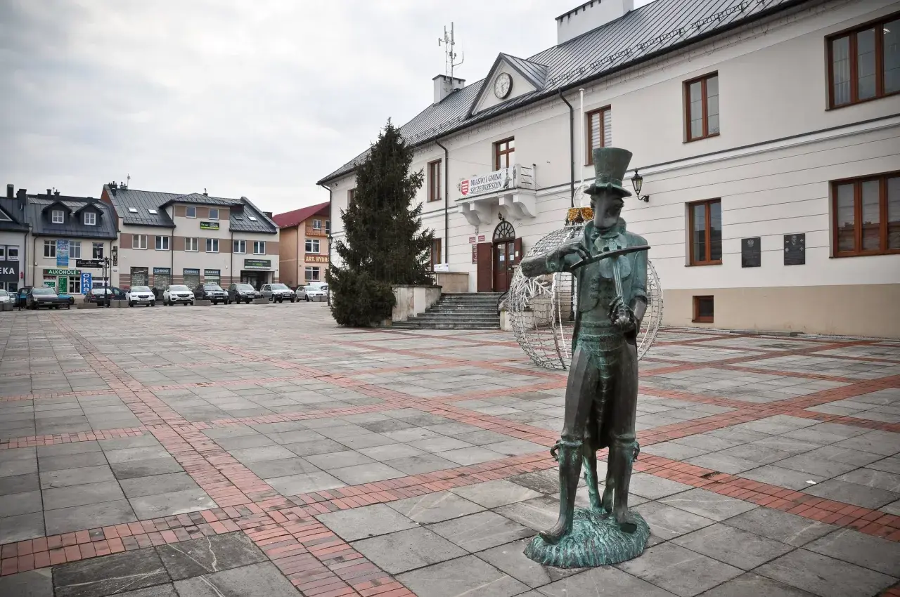 Pomnik chrząszcza w Szczebrzeszynie, jedna z głównych atrakcji miasta, na tle ratusza i placu.