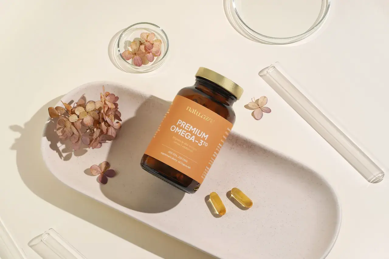 Butelka suplementu Omega-3 z 250 mg DHA, obok kapsułki i suszone kwiaty.