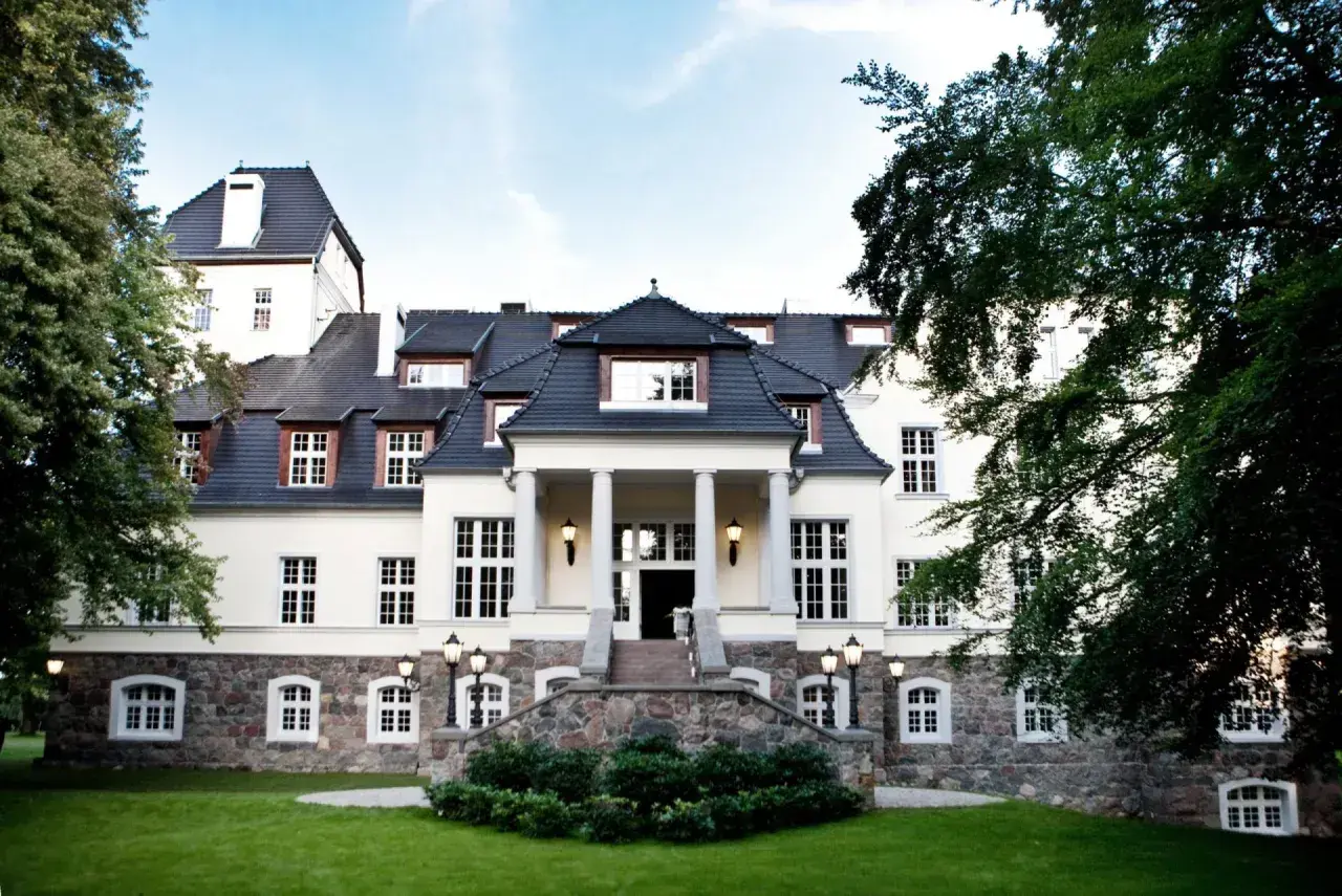 Elegancki pałac w Ciekocinku otoczony zielenią, z kamienną podstawą i kolumnowym wejściem.