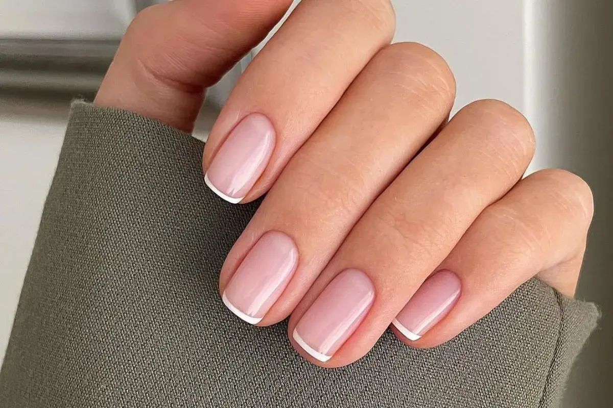 Dłoń z idealnie wykonanymi, eleganckimi paznokciami french. Delikatny róż i klasyczna biel tworzą ponadczasowy manicure.
