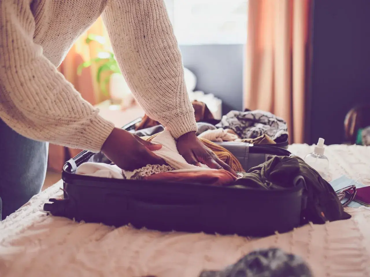 Person packt Kleidung in einen Koffer für den Urlaub. Die Packliste für den Urlaub ist fast komplett.