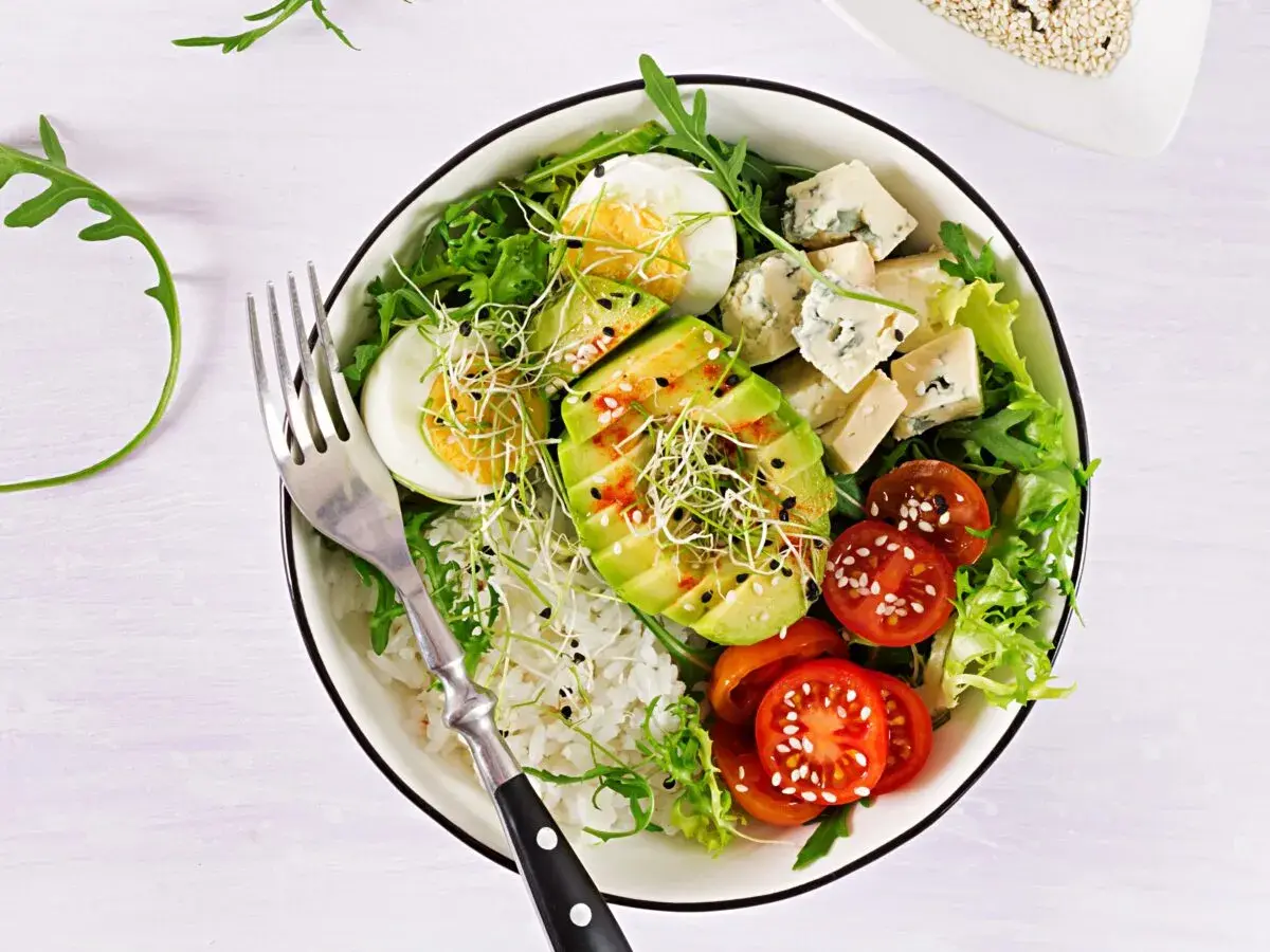 Deliciosa ensalada de aguacate con huevo cocido, queso azul, tomates cherry, brotes y arroz blanco.