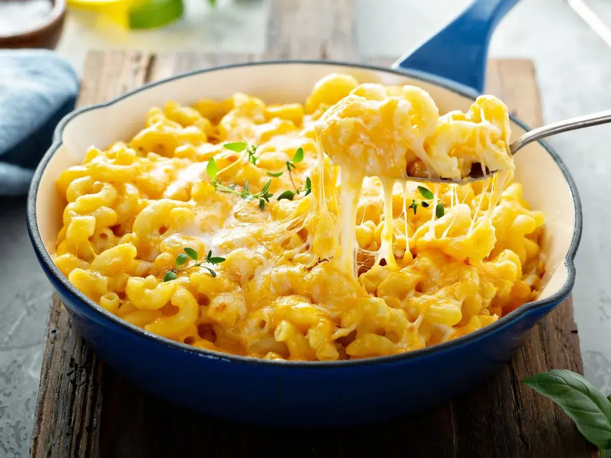 Pyszne, ciągnące się mac n cheese w niebieskiej patelni, z gałązkami tymianku. Idealne na pocieszenie.