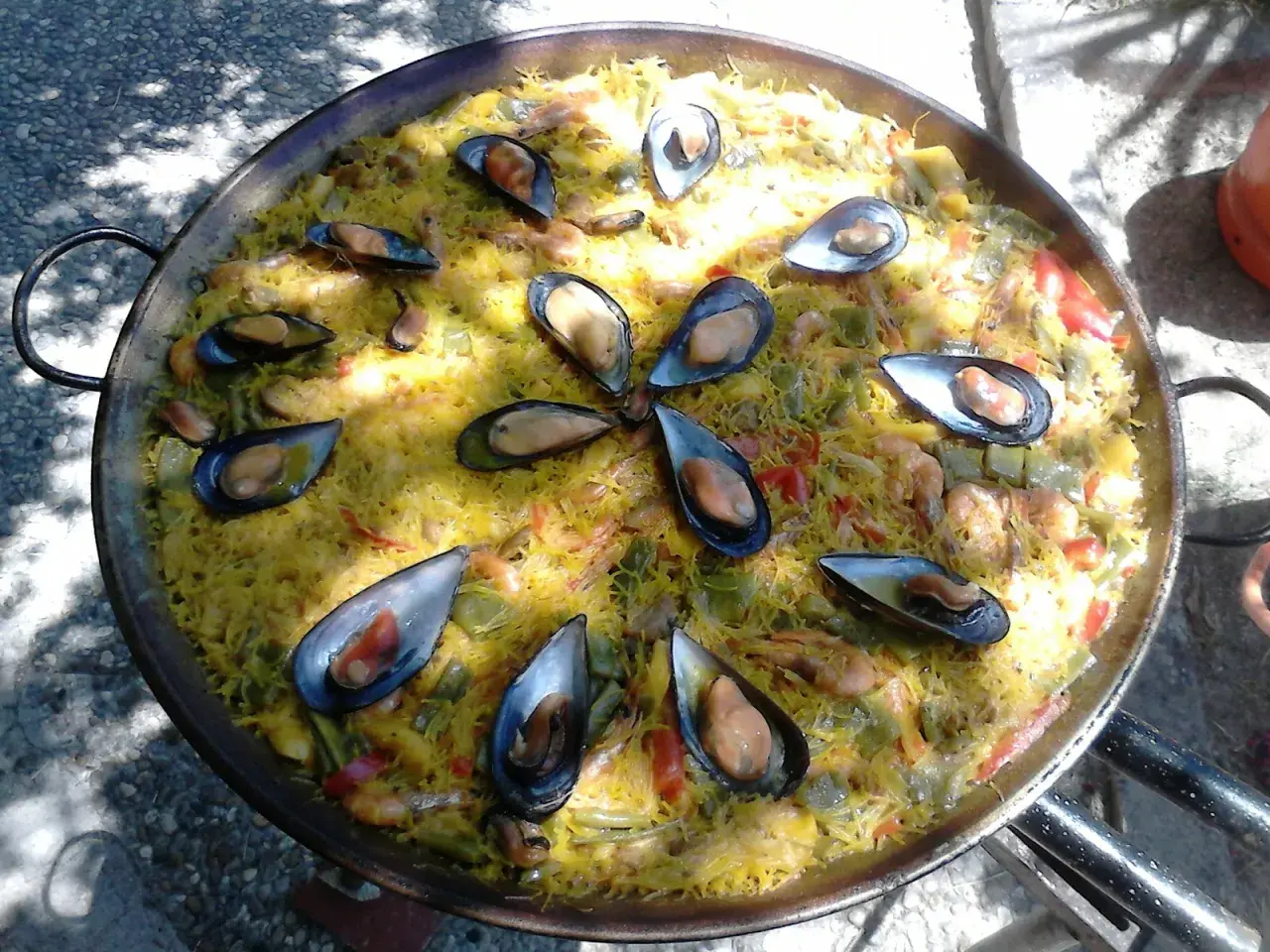 Una deliciosa fideuà mixta, con fideos dorados, mejillones jugosos y gambas, lista para compartir.