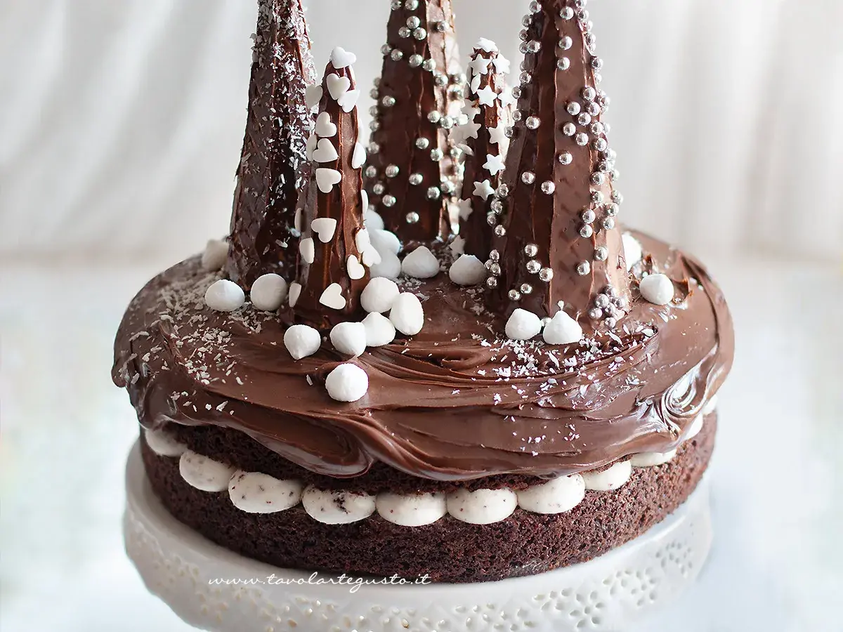 Una magica torta di Natale al cioccolato, decorata con alberelli innevati e dolci fiocchi di neve.