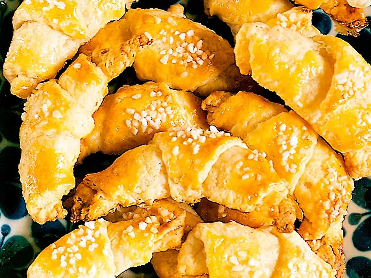 En hög med gyllene gifflar med mandelmassa, toppade med pärlsocker. Perfekta till fikat!