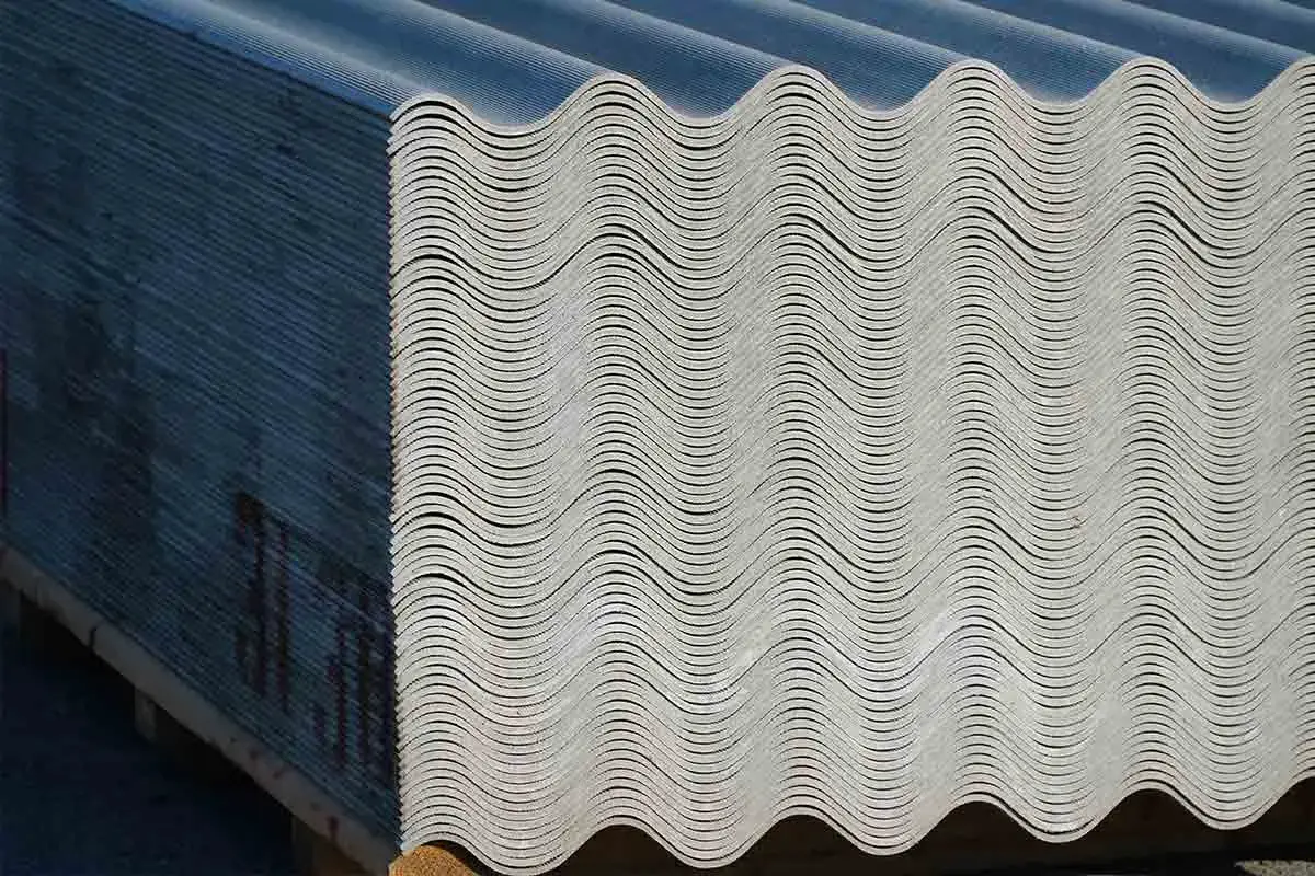 Lastra ondulata in fibrocemento ecologico, impilata su pallet. Materiale da costruzione resistente e durevole.