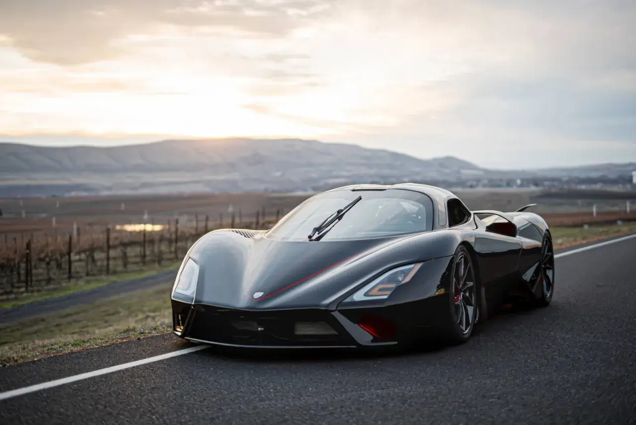 Czarny hypercar SSC Tuatara na drodze z widokiem na wzgórza o zachodzie słońca.