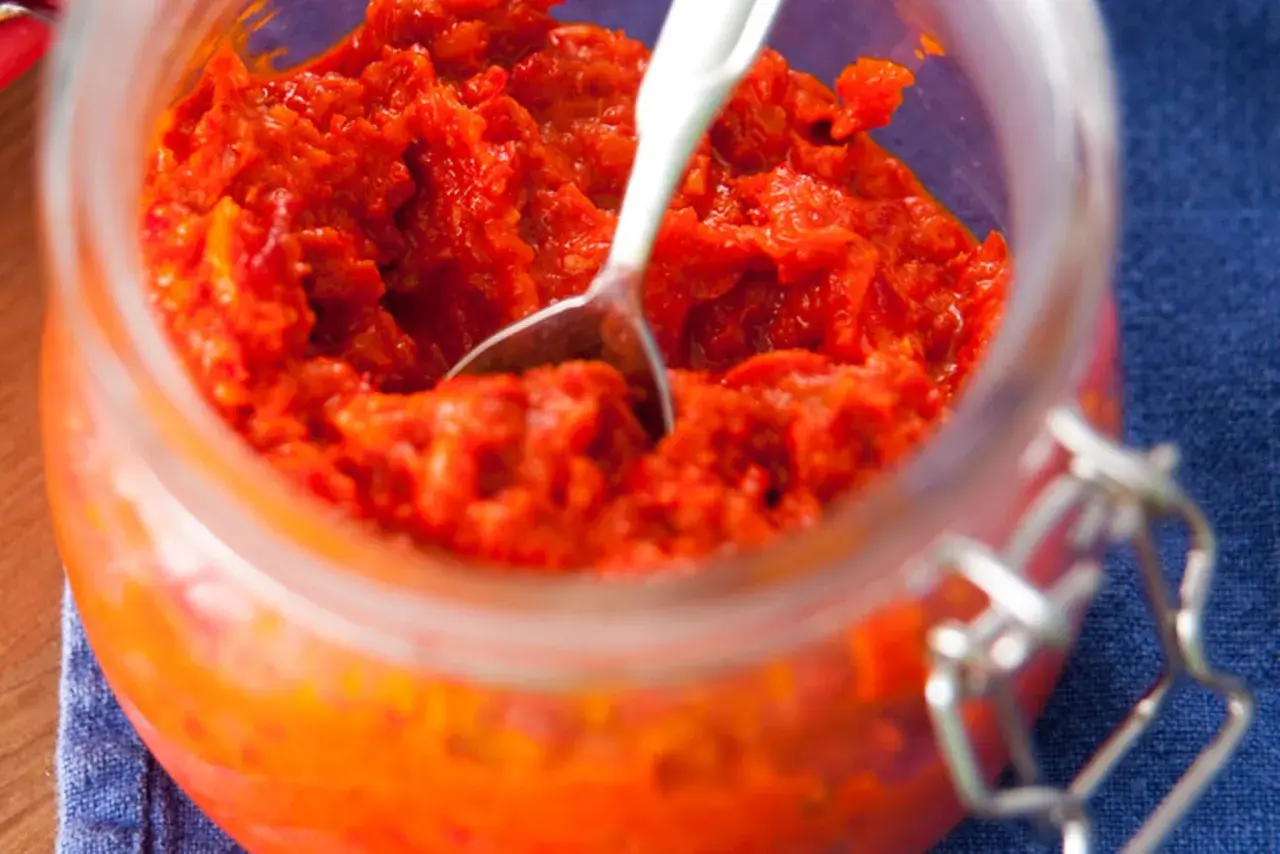 Ein Glas mit selbstgemachtem Ajvar, bereit zum Genießen. Dieses Ajvar Rezept ist ein Muss für jeden Liebhaber von herzhaften Aufstrichen.