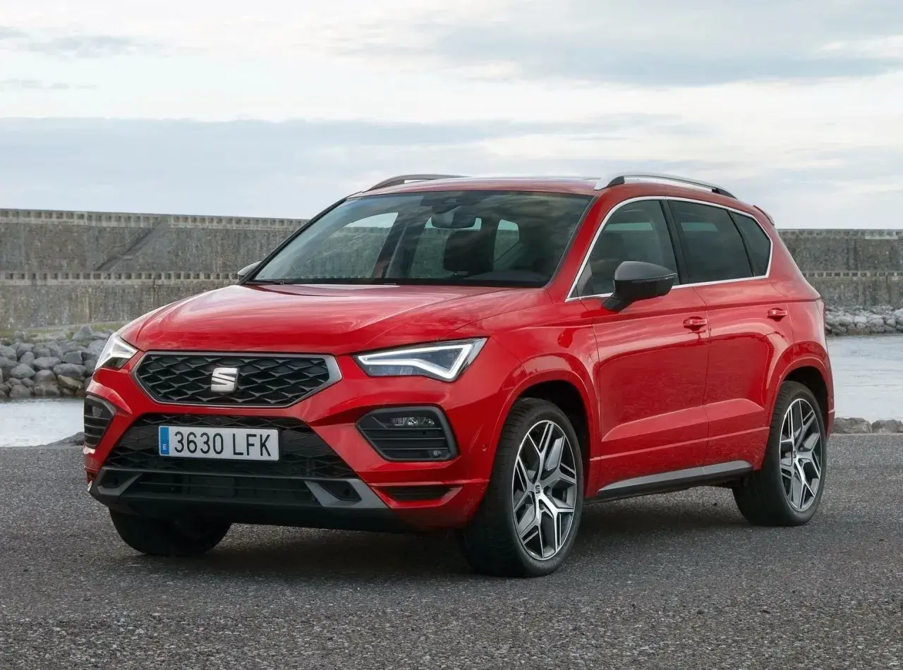 Czerwony Seat Ateca na tle kamiennego nabrzeża. Wiele osób szuka seat ateca opinie przed zakupem.