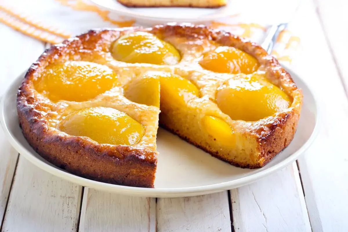 Torta soffice con pesche sciroppate dorate, un dolce profumato e invitante, perfetto per ogni occasione.