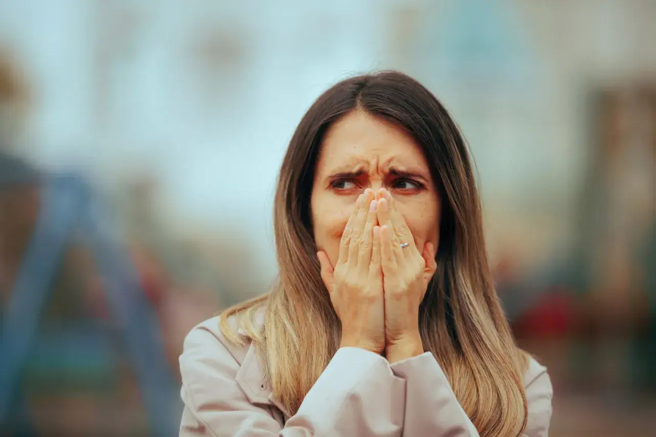 Donna con mani sul viso, espressione di ansia. Potrebbe cercare agorafobia rimedi veloci per superare la paura degli spazi aperti.