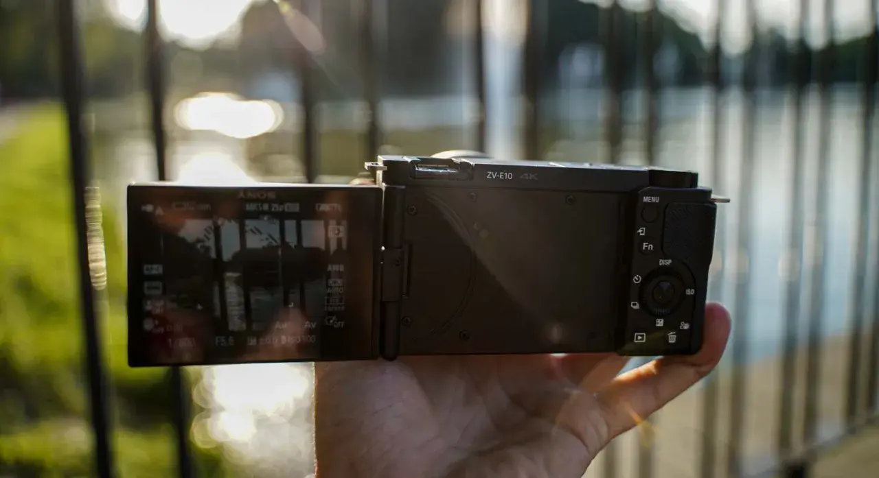 Dłoń trzyma aparat Sony Alpha ZV-E10 z uchylonym ekranem, na którym widać ustawienia nagrywania 4K.