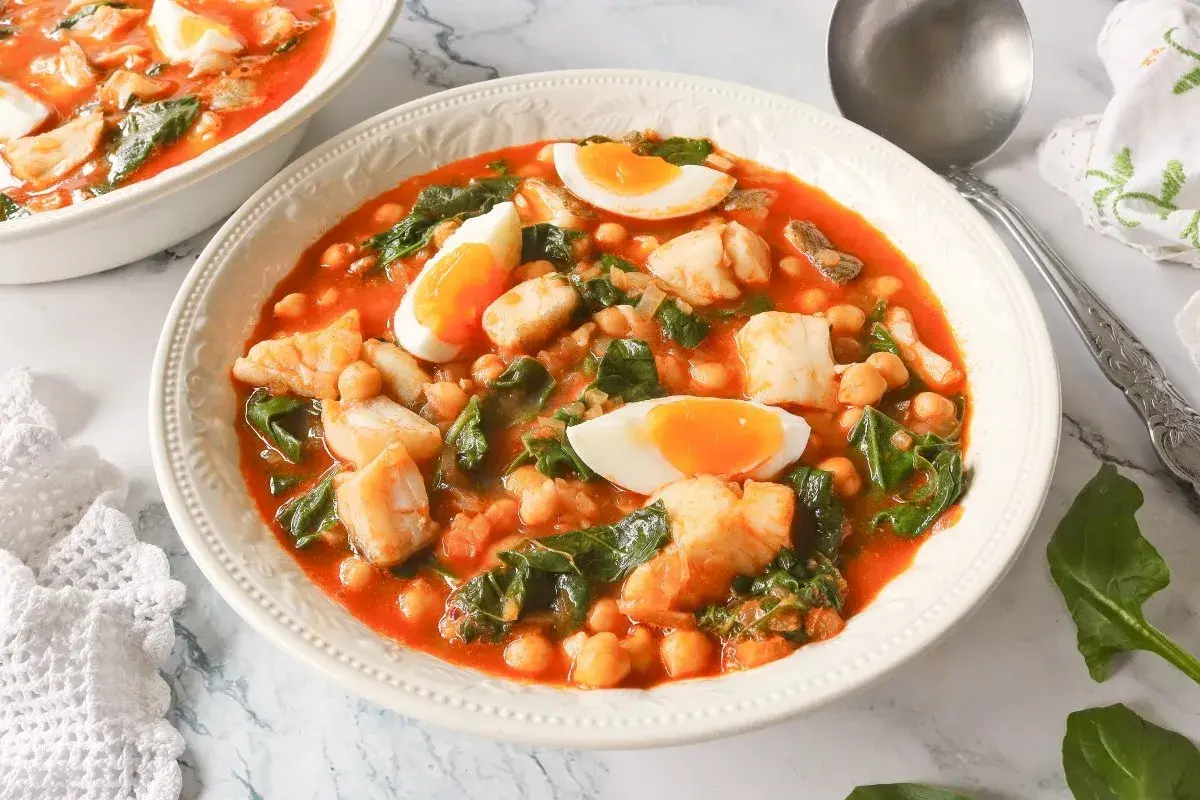 Un reconfortante potaje de vigilia con garbanzos, espinacas y trozos de pescado blanco, coronado con huevos duros.