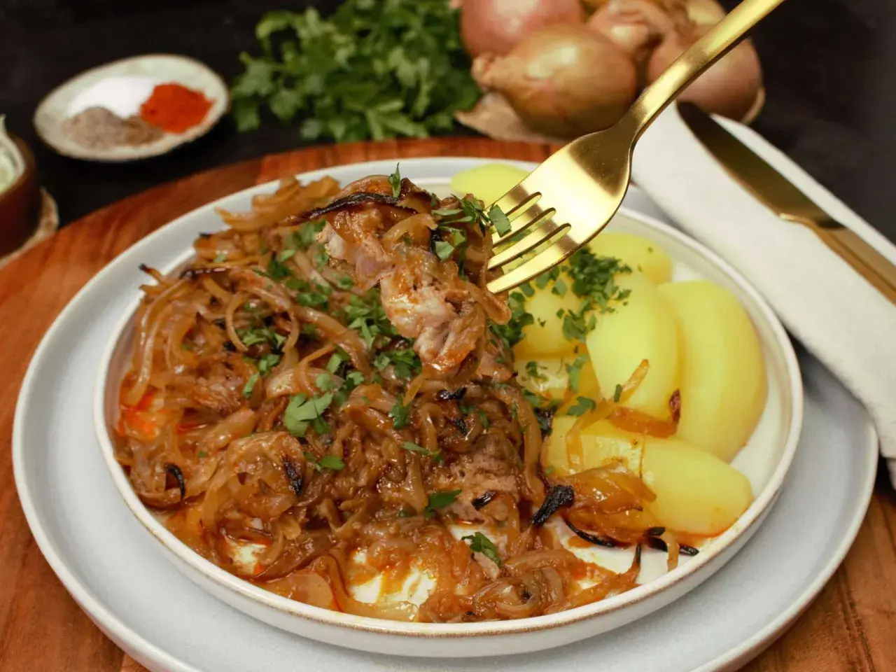 Zwiebelfleisch nach Omas Art: Zartes Fleisch mit karamellisierten Zwiebeln und Salzkartoffeln, garniert mit Petersilie. Ein Klassiker, der immer schmeckt.