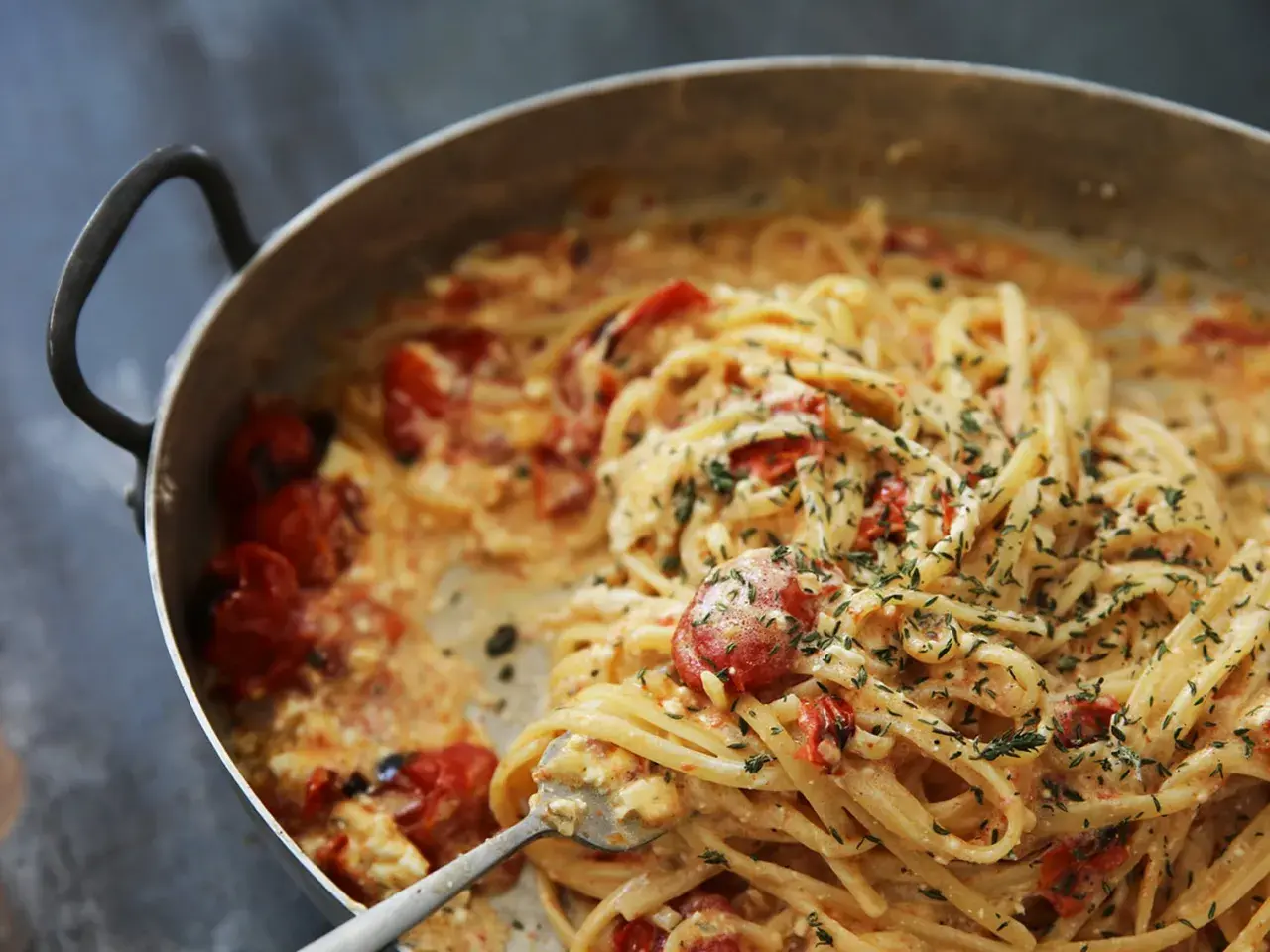 Pâtes crémeuses aux tomates cerises et herbes fraîches, servies dans une poêle. Un délice !