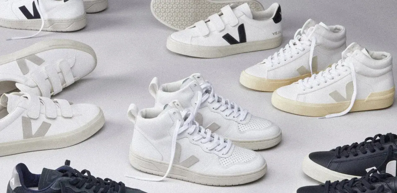 Kolekcja białych i granatowych butów Veja, w tym modele na rzepy i wysokie. Veja to marka znana z ekologicznych sneakersów.