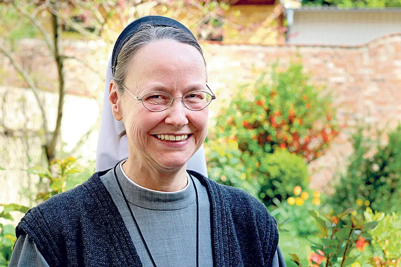 Lächelnde evangelische Nonne mit Brille im Garten.