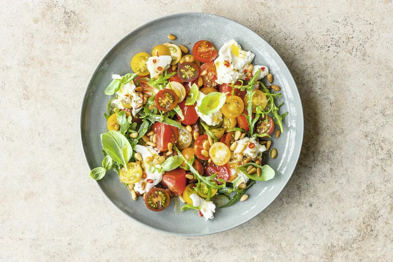 Bunter Tomatensalat mit Burrata, Rucola und Pinienkernen. Ein leichter Genuss für warme Tage.