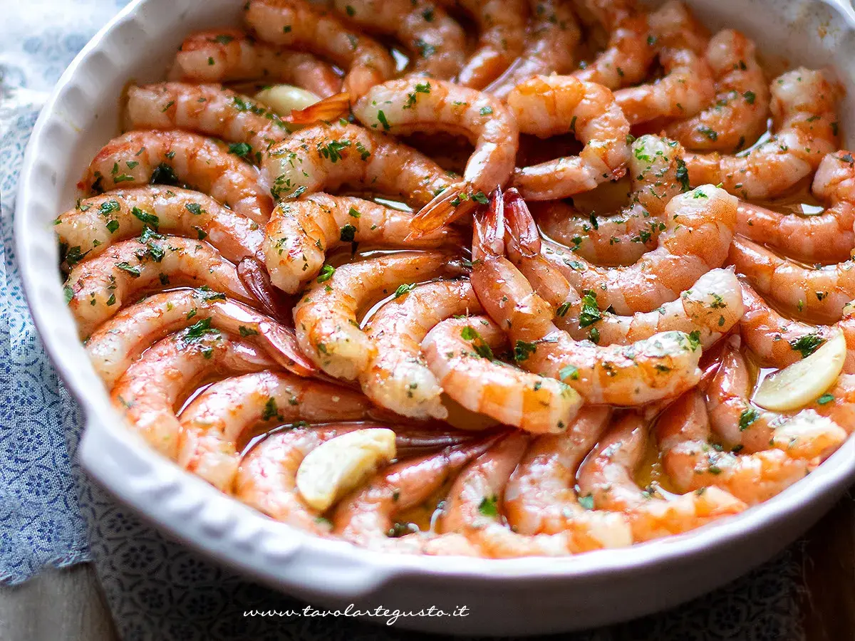 Gamberoni al forno succulenti, conditi con aglio e prezzemolo, pronti per essere gustati.