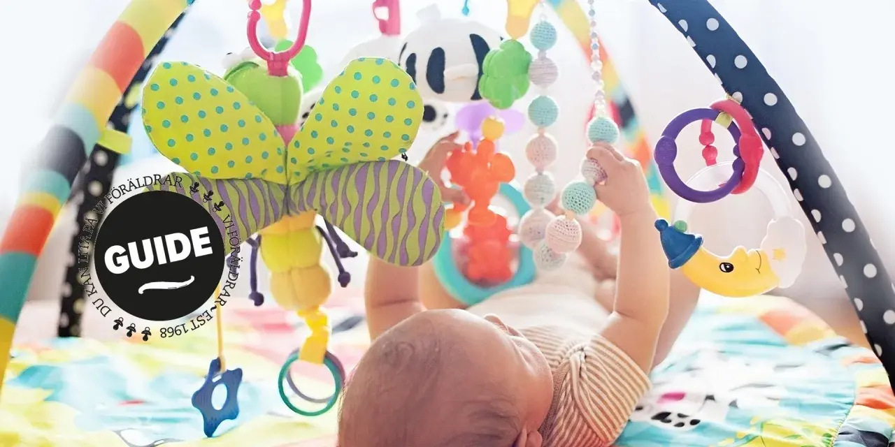 En bebis leker under en färgglad babygym med en söt kanin som hänger.