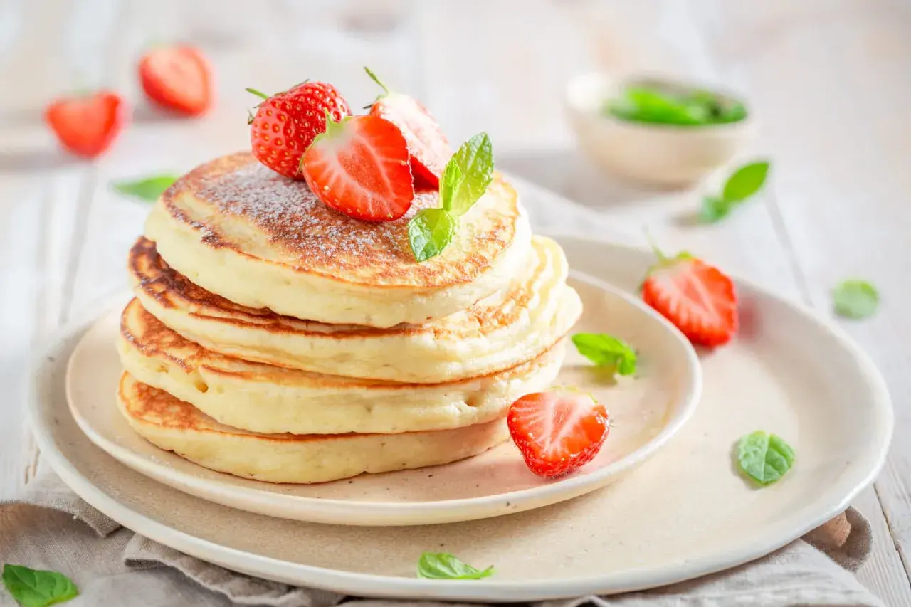 Pile de pancakes moelleux, décorés de fraises fraîches et de menthe, comme ceux de Cyril Lignac. Un délice !