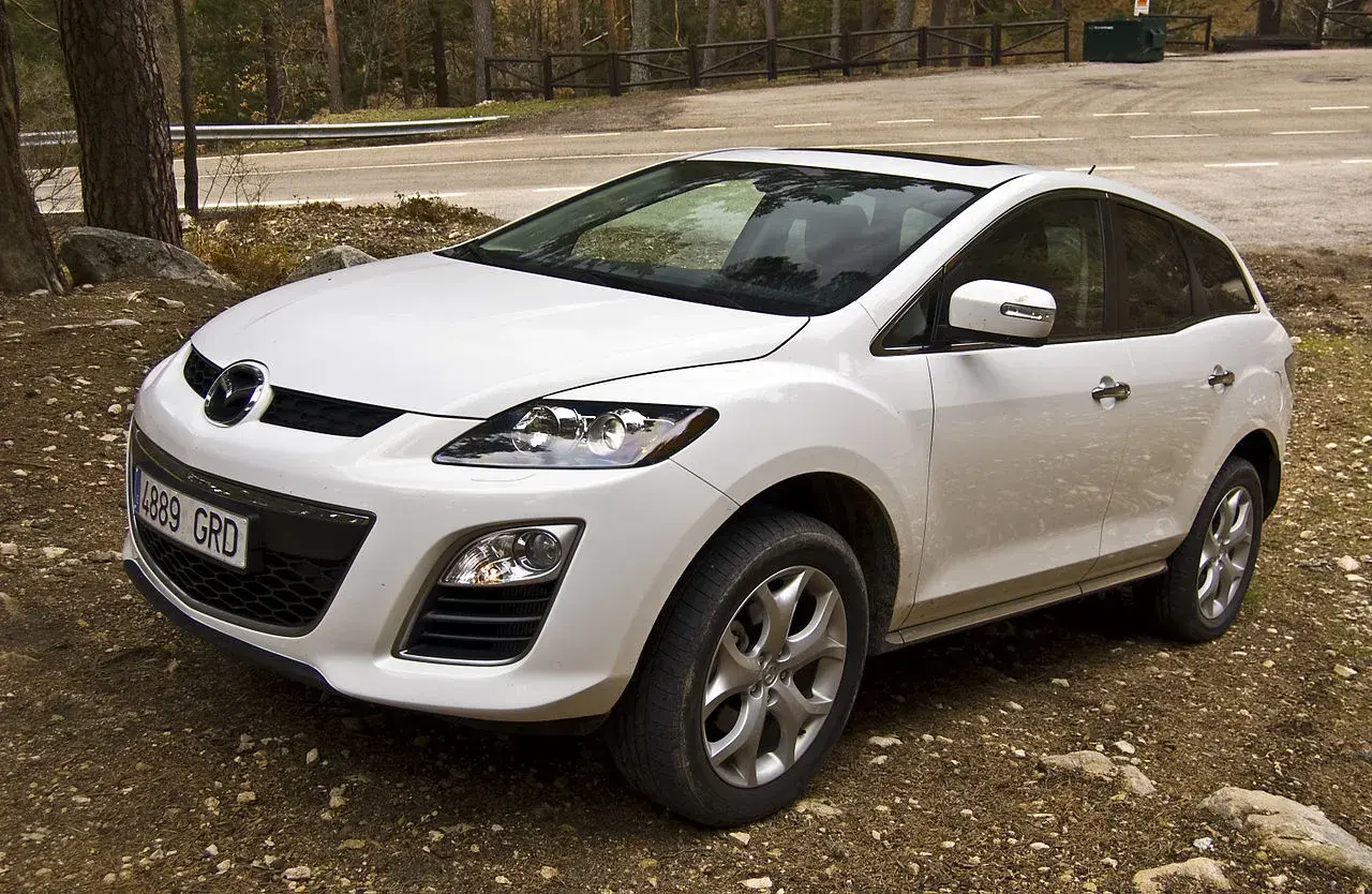 Biała Mazda CX7 zaparkowana na leśnej drodze.
