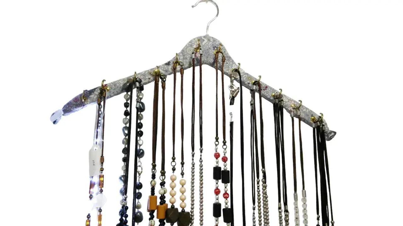Percha para collares con multitud de cadenas y colgantes de diversos materiales y colores, organizados de forma ordenada.