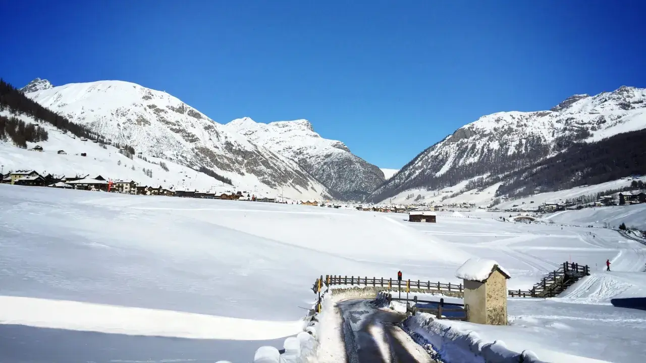 Paysage hivernal à Livigno, Italie. Montagnes enneigées, village pittoresque et route dégagée sous un ciel bleu éclatant.