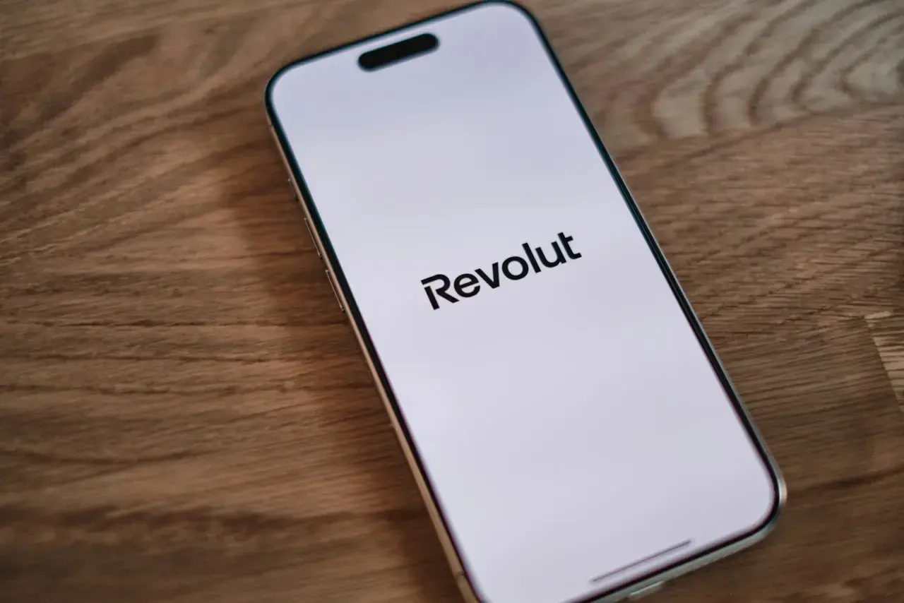 Telefon z logo Revolut na ekranie. Dowiedz się, jak wplacić pieniadze na Revolut, aby łatwo zarządzać finansami.