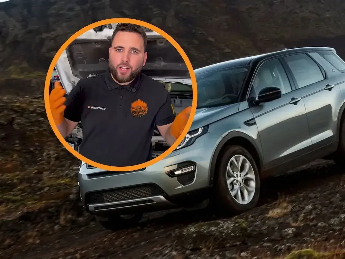 Opiniones sobre el motor Land Rover 3.0 TDV6. Mecánico con guantes naranjas habla junto a un Land Rover Discovery en terreno accidentado.