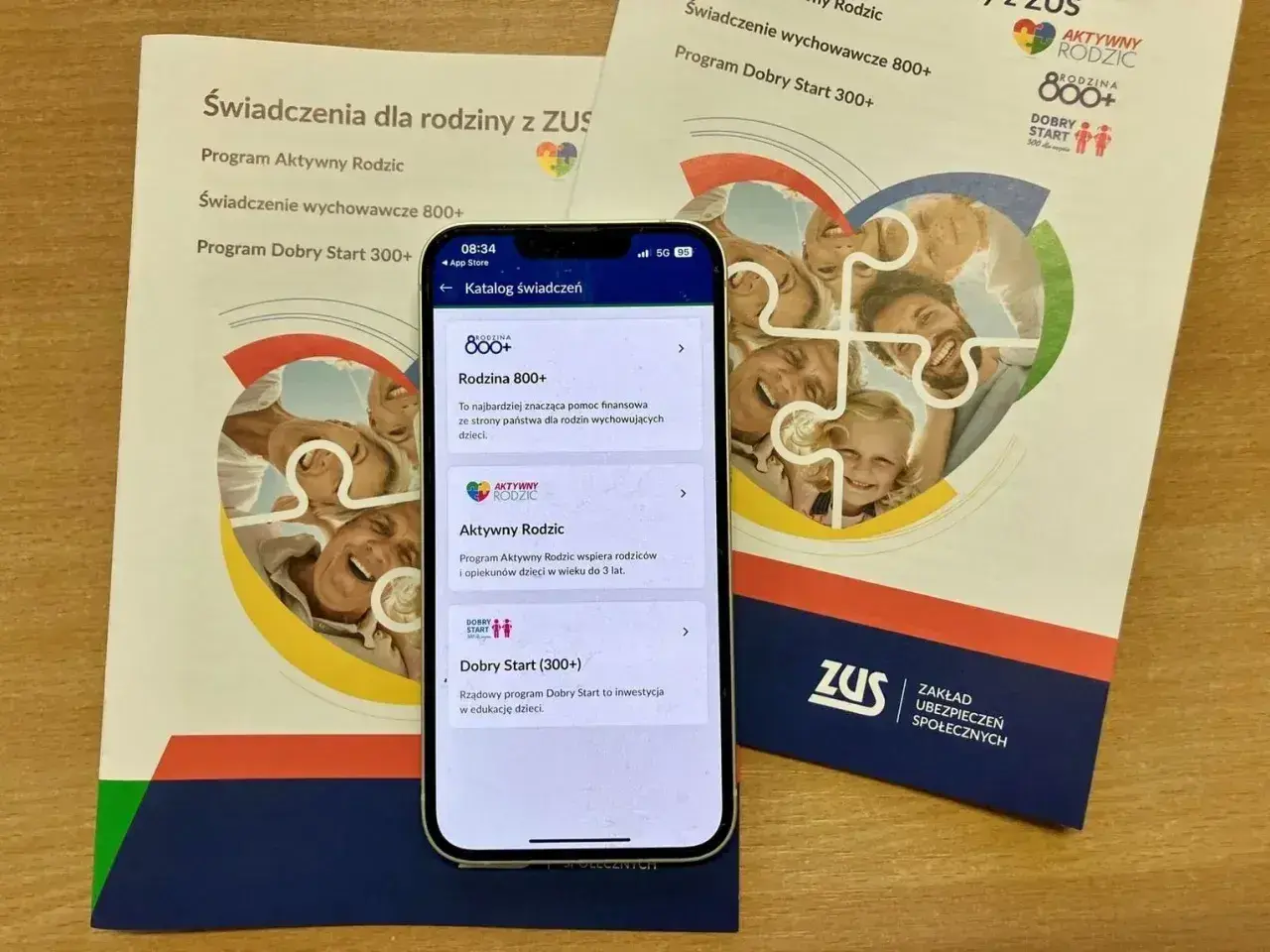 Program Dobry Start 300+ to dobry start dla każdego dziecka, wspierany przez ZUS. Na ekranie telefonu widać katalog świadczeń.