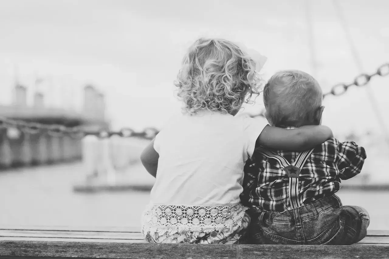 Due bambini, cugini, si abbracciano guardando il mare. Un tenero legame che ricorda un amore puro, lontano da ogni malizia.