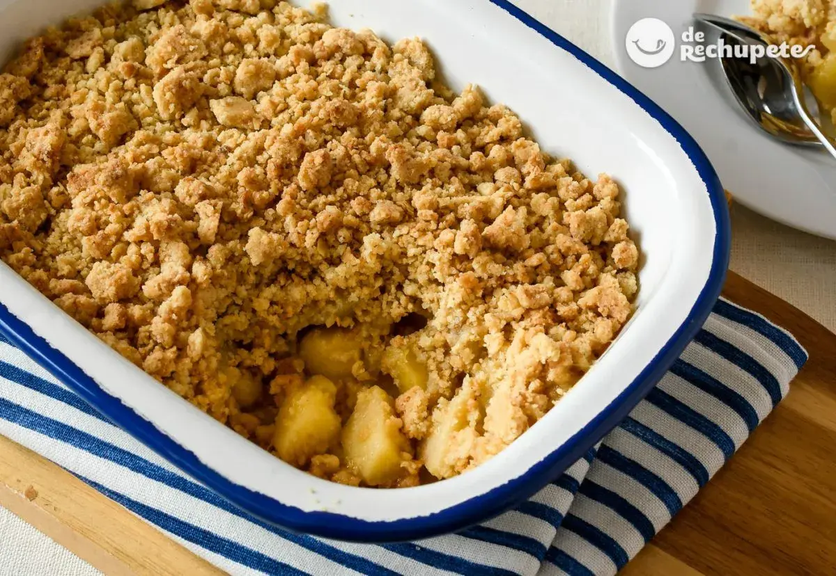 Un delicioso crumble de manzana recién horneado, con trozos dorados de manzana bajo una capa crujiente de migas.