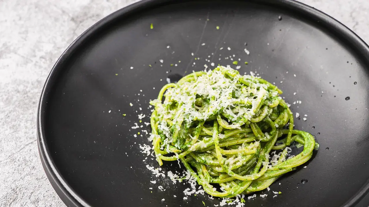 Ein Teller mit leckeren Nudeln mit Pesto, bestreut mit frisch geriebenem Parmesan.