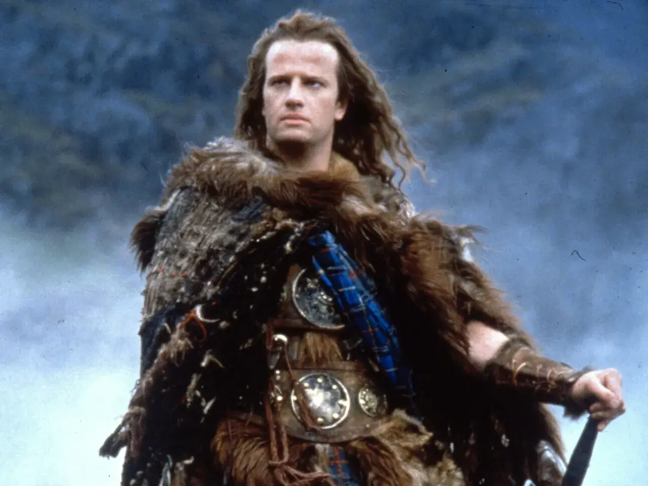 Christopher Lambert w filmach jako nieśmiertelny wojownik w futrzanej zbroi, gotowy do walki.