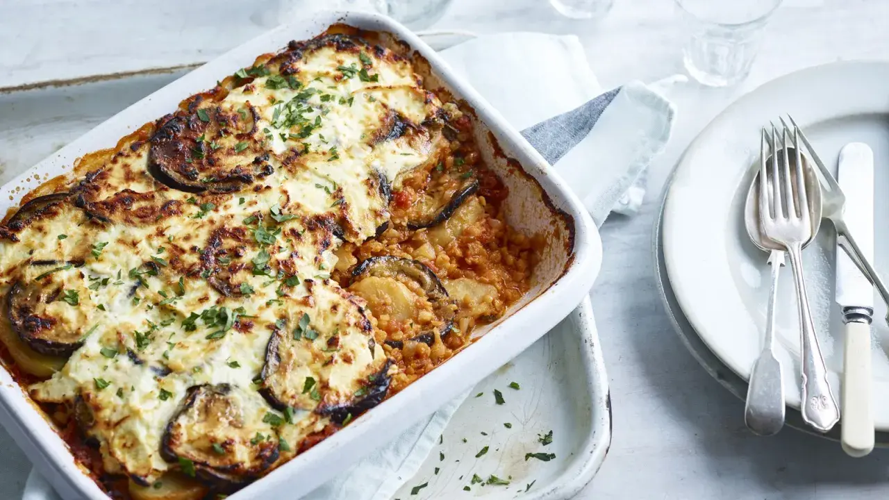 Un plat de moussaka végétarienne gratinée, garni d'aubergines et de persil frais, prêt à être dégusté.