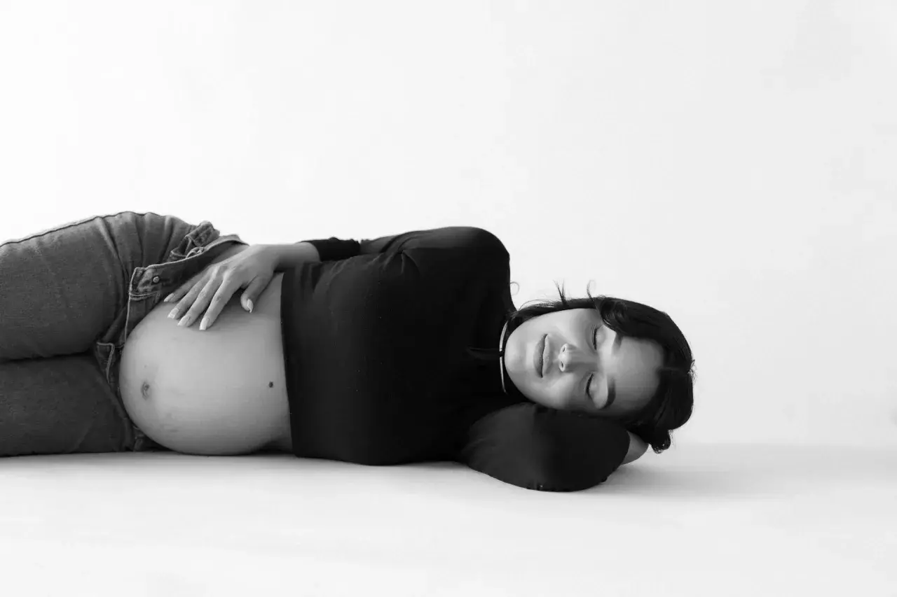 Donna incinta dorme serena, con la mano sul pancione. La vena cava è compressa, ma la serenità della gravidanza prevale.