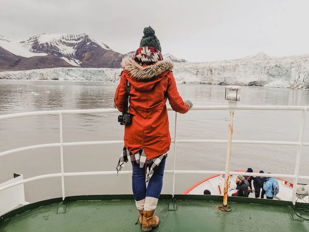 Podróżniczka podziwia lodowce na archipelagu Svalbard. W oddali widać góry i morze.
