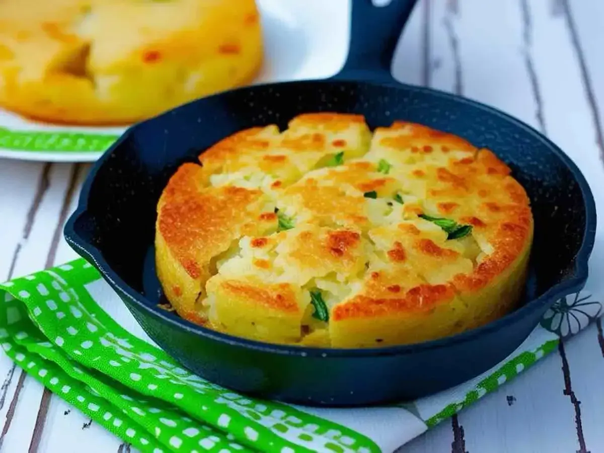 Tortino di patate prosciutto e mozzarella dorato e fragrante, servito in una piccola padella di ghisa.
